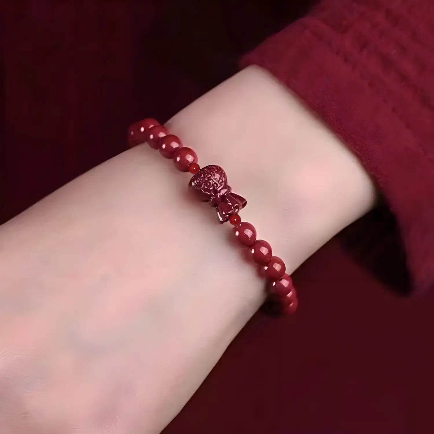 A handcrafted cinnabar lotus and calabash beaded bracelet featuring a vibrant red color and a detailed glossy buddha charm as its centerpiece.