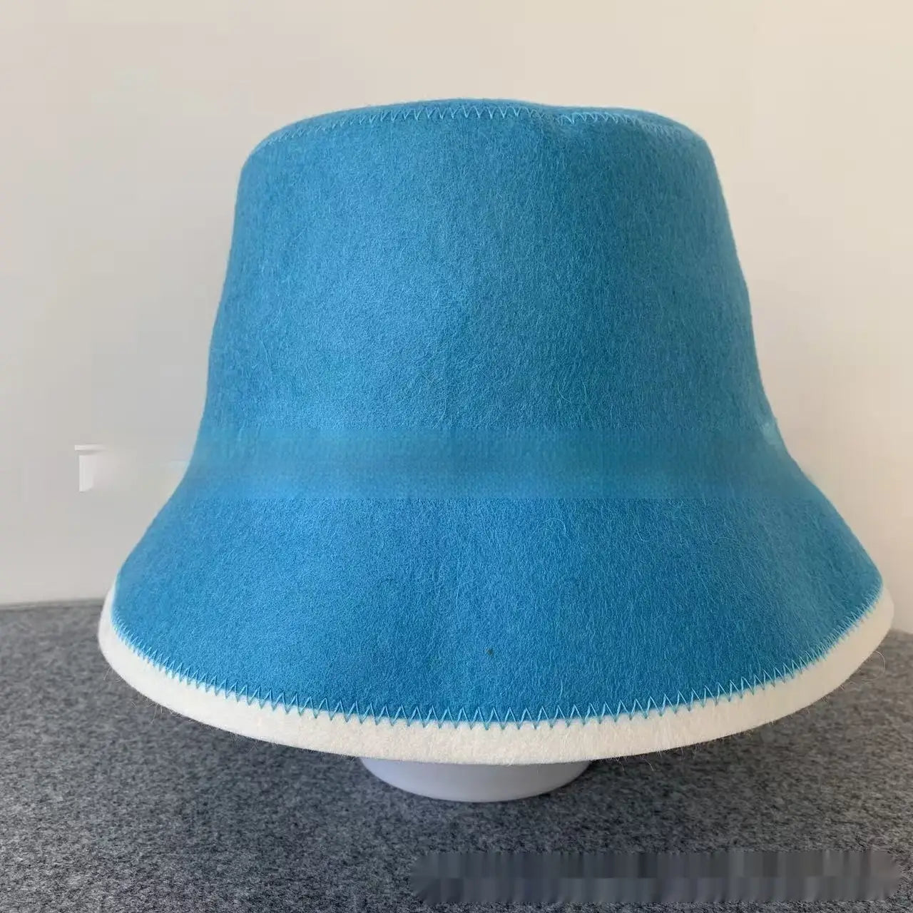 A vibrant blue wool felt sauna cap bucket hat featuring a contrasting white stitched trim around the brim.