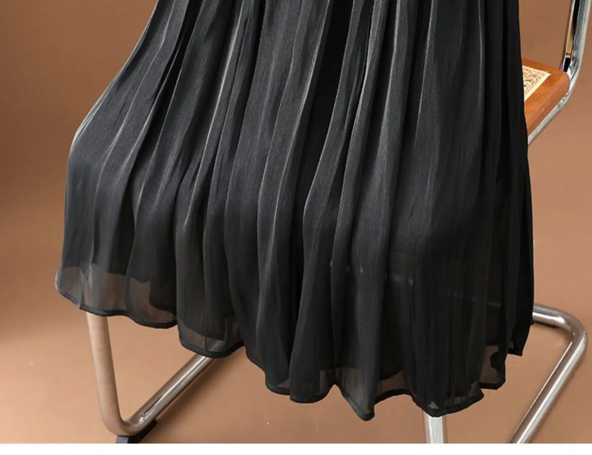 Ein schwarzer irrisierender Chiffon-Faltenrock aus leicht fließendem, transparentem Gewebe, geeignet für elegante Anlässe.