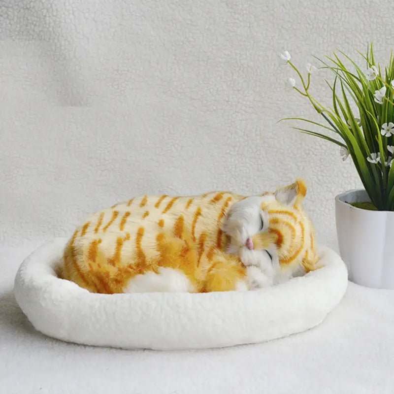 A plush orange and white tabby realistic breathing cat figurine nestled in a soft round white pet bed.