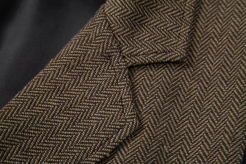 Detalle del cuello del blazer de espiga marrón de un chaleco de traje tipo sastre doble abotonado de espiga para hombre.