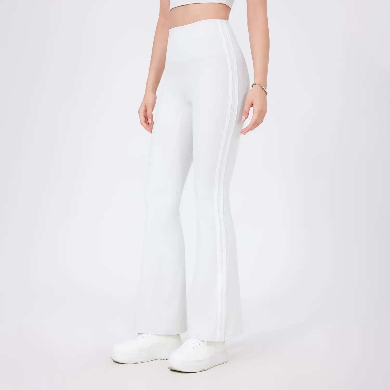 Leggings de yoga évasés taille haute blancs avec un tissu extensible et élégant, ainsi que des bandes latérales discrètes.