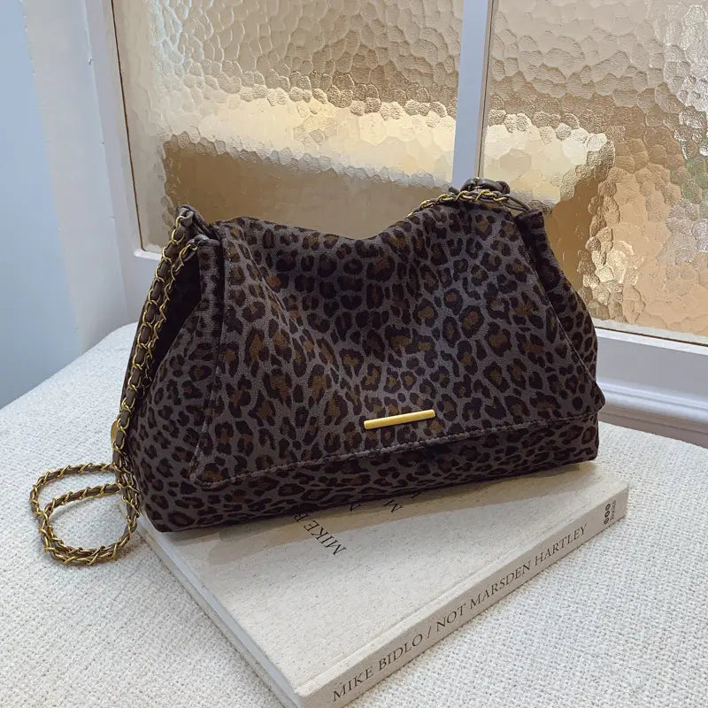 Brown leopard-print crossbody bag with gold-tone chain strap and matching metallic clasp designed for stylish everyday use.