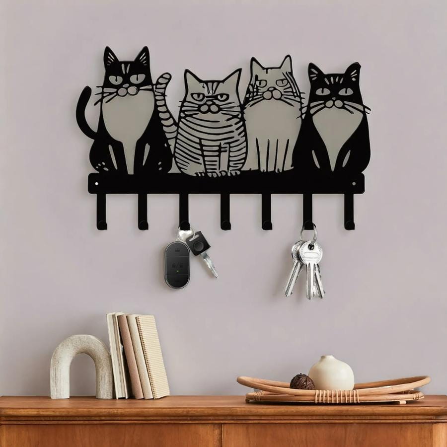 Black metal wall-mounted key holder with four stylized cats in a row featuring distinct facial expressions and patterns for home decor.