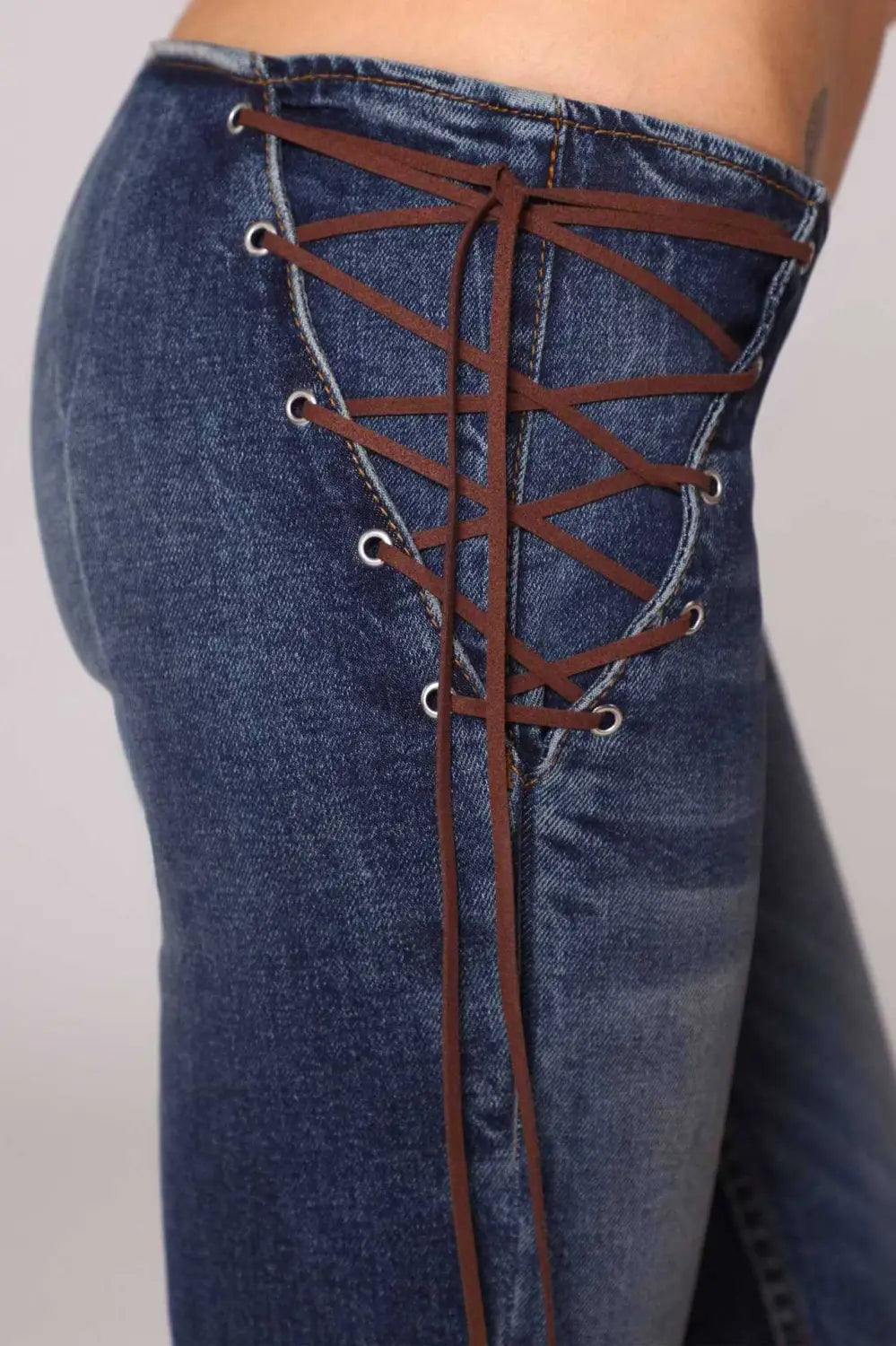 jeans de mezclilla de tiro bajo tipo campana en mezclilla azul con detalles de encaje con cordones marrones en la parte posterior