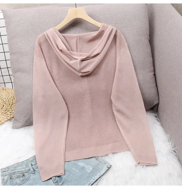Ein weichrosa Blush-Pink gestricktes Hoodie-Cardigan mit gerippter Struktur und langen Ärmeln, präsentiert auf einem Holzkleiderbügel.