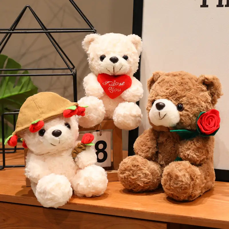 Ein weißer Plüsch-Teddybär trägt eine beigen Hut, der mit roten Rosen verziert ist, und hält einen kleinen Strauß; er sitzt neben einem braunen Teddybären, der mit einer roten Rose dekoriert ist, in einem Teddybär-Plüschtier mit Rosen, Valentinsgeschenk, 16–25 cm.