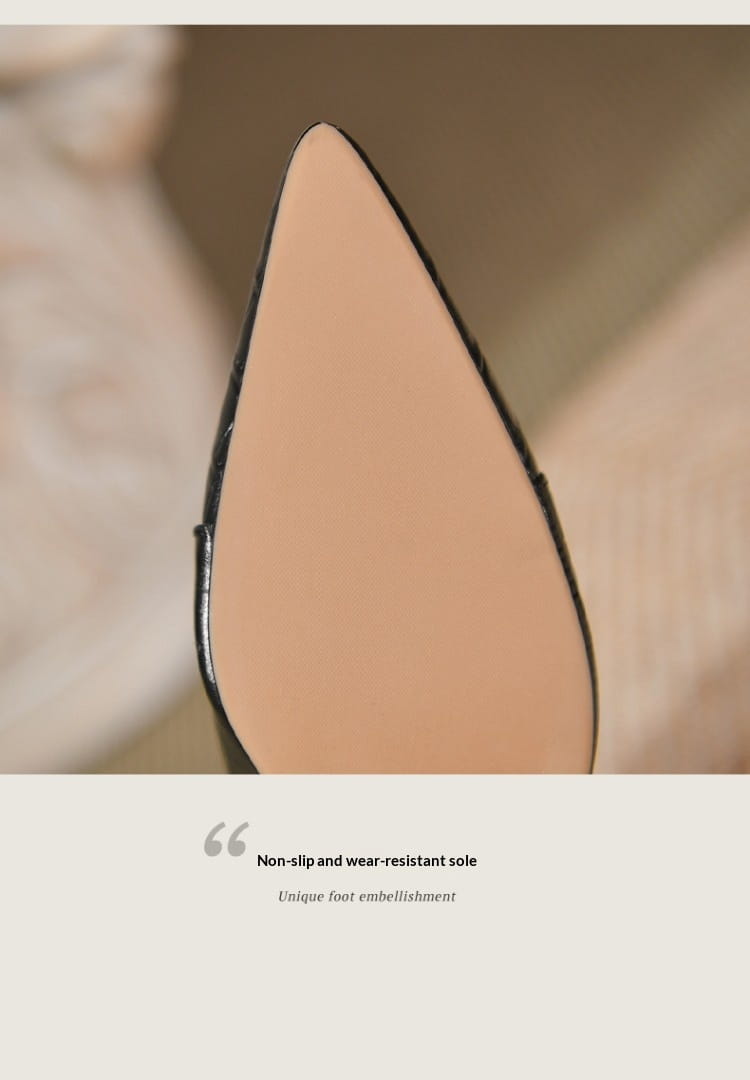 A sleek black and nude-colored sole of croc embossed leather stiletto ankle boots with a pointed toe design.
