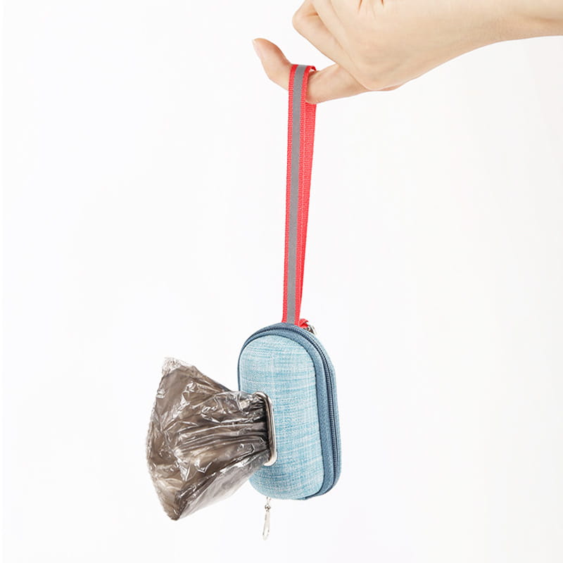 Light blue denim-textured dog poop bag dispenser with a red reflective strap and silver metal clip for convenient pet waste disposal.