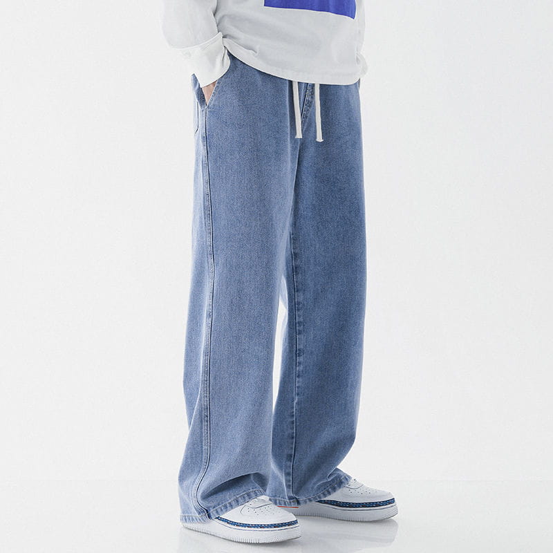 Men’s relaxed fit drawstring wide leg denim jeans in light-wash blue denim with a drawstring waistband.