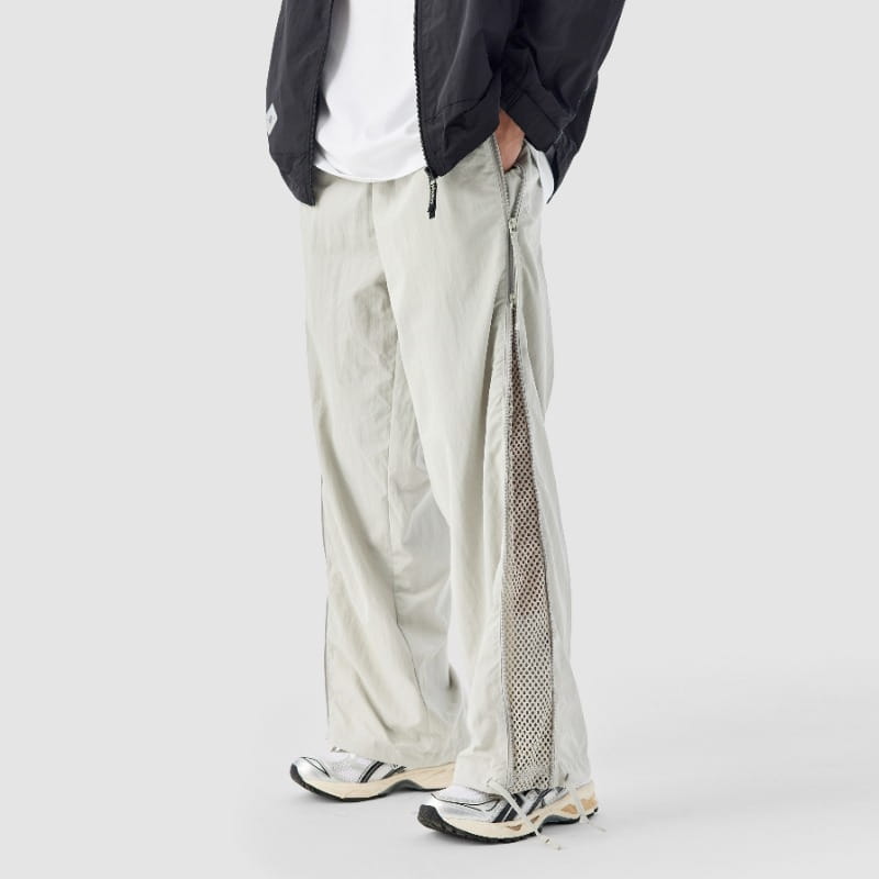 Pantalon de randonnée utilitaire à jambe large en gris clair avec un panneau en mesh le long de la couture latérale.