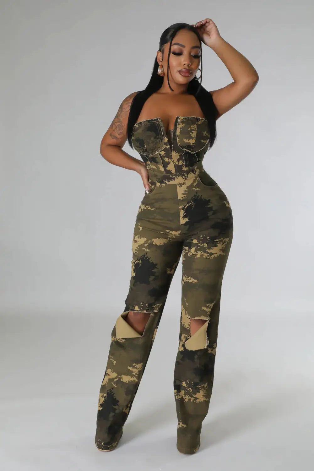 Camouflage-Aussteller-Jeansjumpsuit mit einem Design für ausgefranste Knie-Risse und einem Korsett-ähnlichen Oberteil in einer Camouflage-Optik.