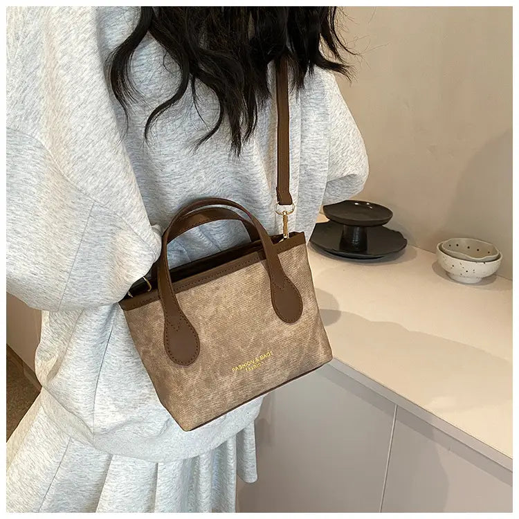 Beige textured canvas mini tote with brown leather handles and trim shown as a retro bucket bag textured canvas shoulder handbag.