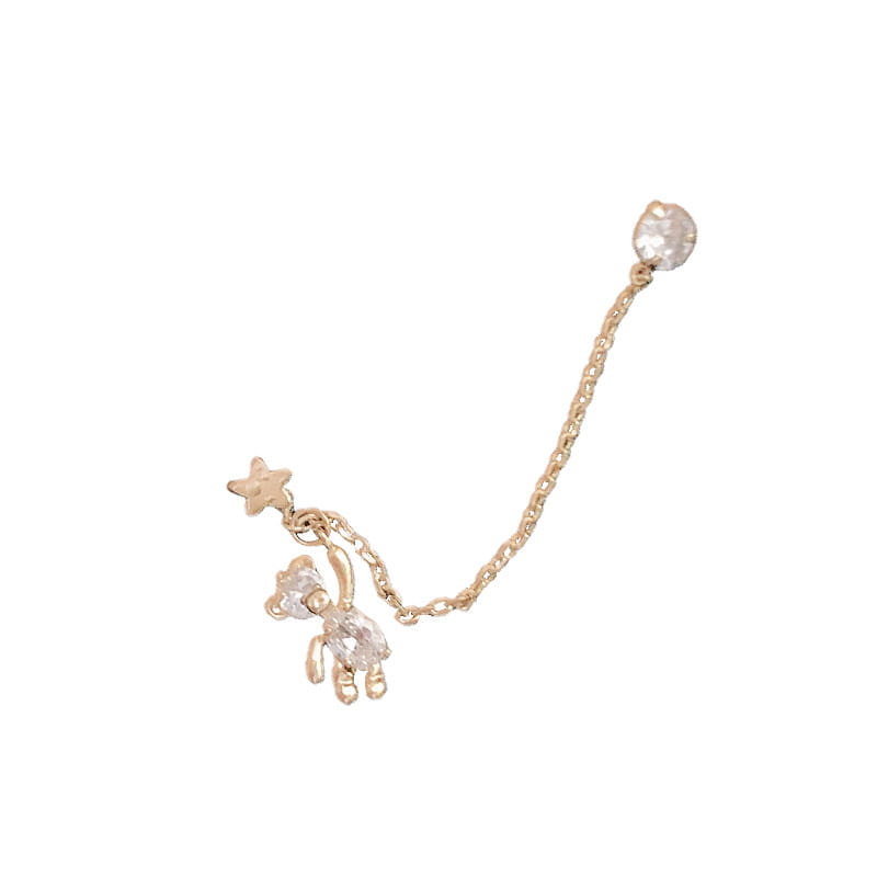 Boucle d’oreille asymétrique en strass à finition dorée, avec un pendentif ours suspendu orné de cristaux transparents et d’un accent étoilé, relié par une chaîne réglable à un cabochon rond en cristal.