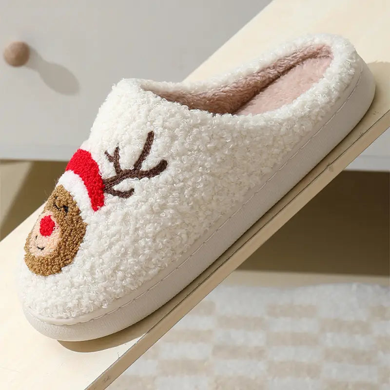 white fluffy slipper featuring an embroidered reindeer face with a red santa hat and brown antlers from festive embroidered santa and reindeer winter slippers collection