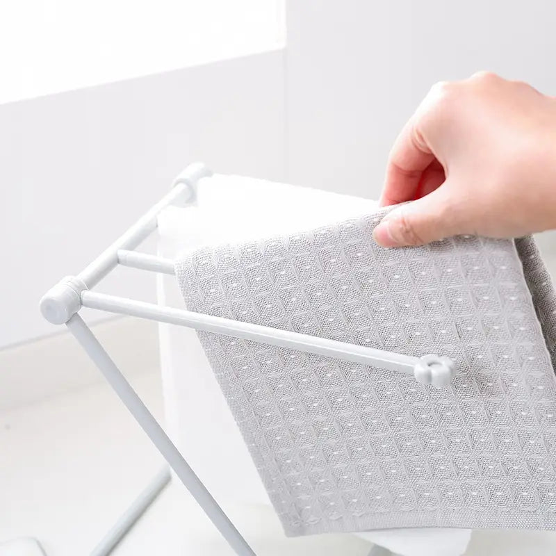 a light gray textured towel with a subtle pattern hanging from a minimalist white plastic foldable dishcloth rack kitchen towel organizer shelf