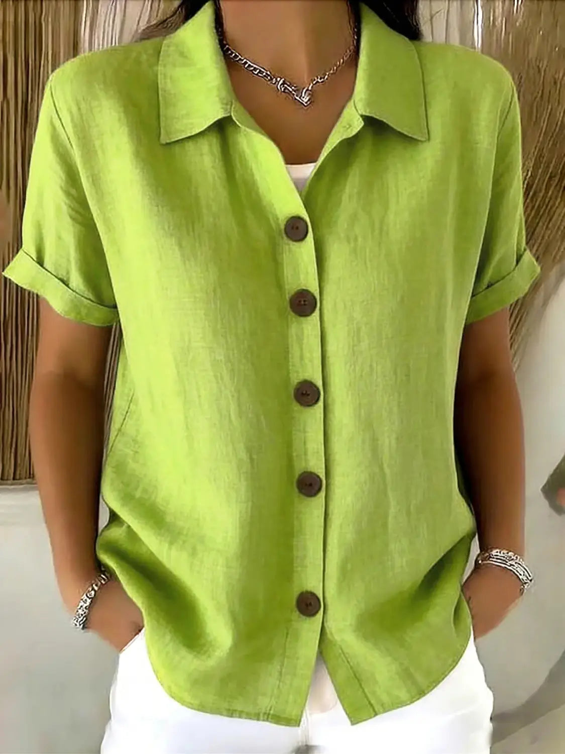 Camisa abotonada de lino para mujer de manga corta en verde lima vibrante, elaborada con una mezcla de lino, con cuello clásico y botones marrón oscuro.