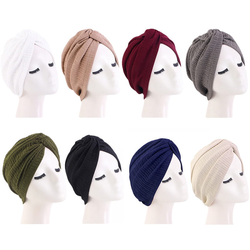 Eine Sammlung von acht weichen, fein gerippten Turban-Headwraps in einfarbigen Farben, darunter Olivgrün, Beige, Burgunderrot, Grau, Marineblau, Schwarz, Weiß und Creme; entworfen als ethnische Sonnenhüte.