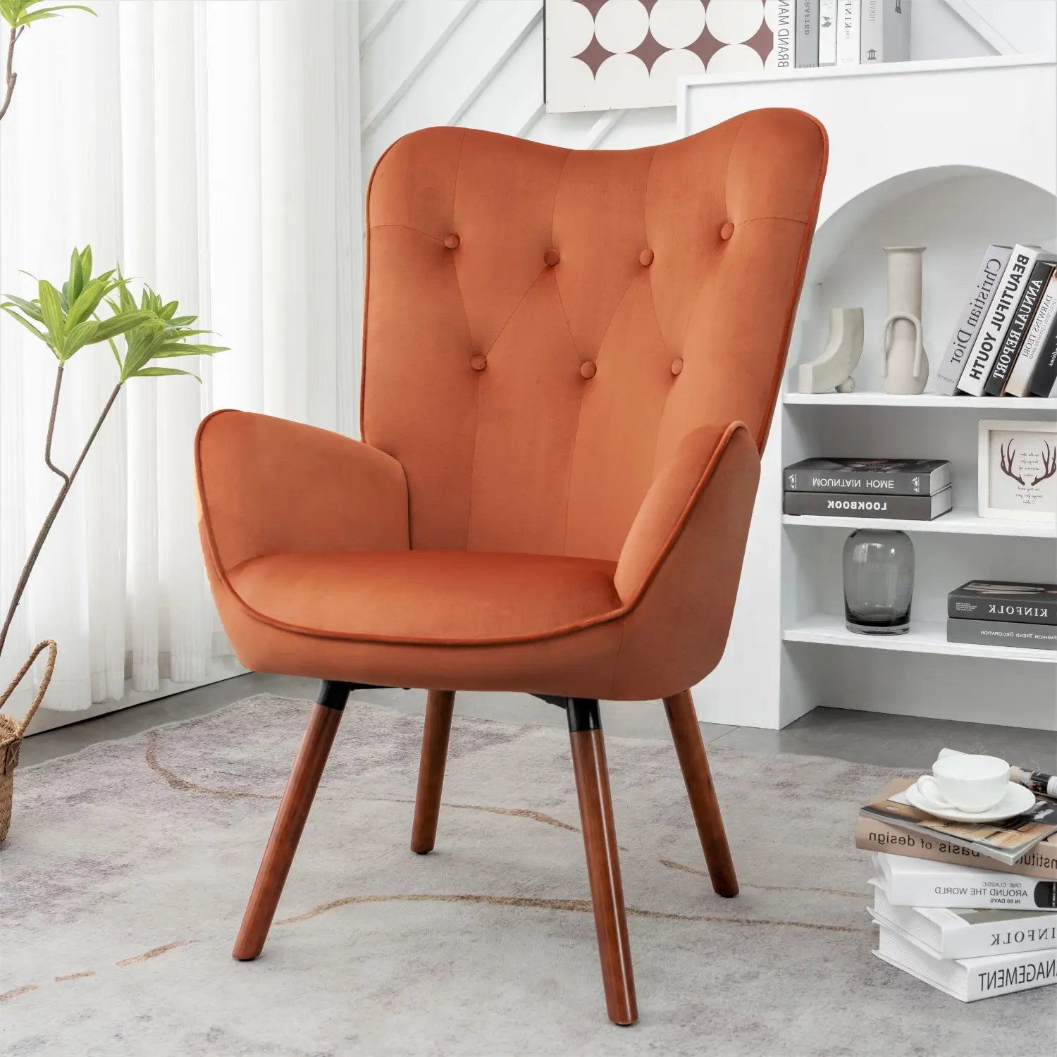 Una acogedora silla de acento tipo wingback de estilo moderno de mediados de siglo en color naranja, con tapizado con capitoné y patas de madera.