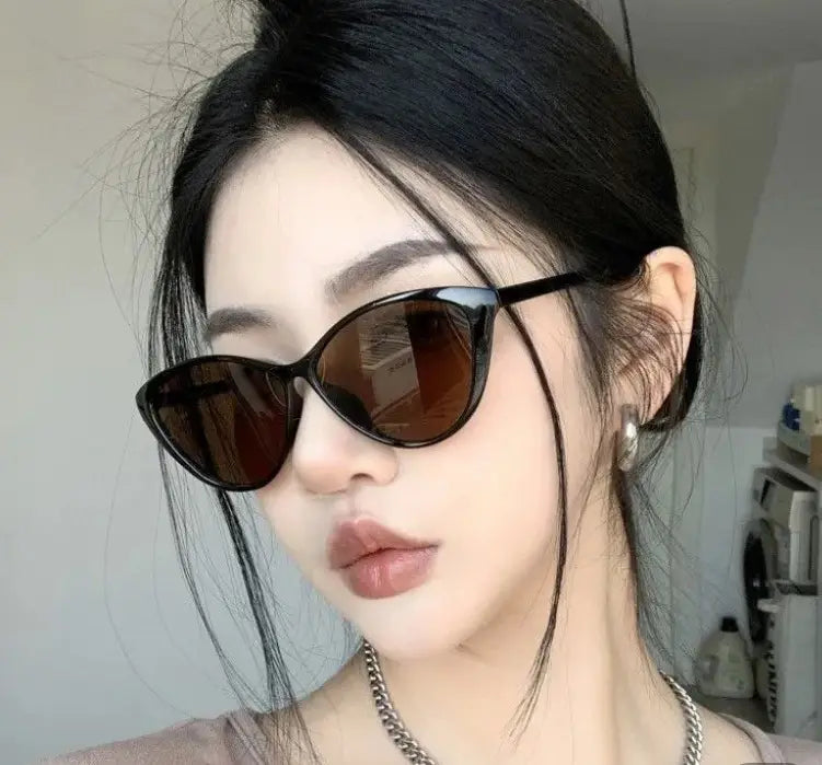 Lunettes de soleil œil-de-chat noires avec des verres brun foncé, offrant une protection UV380 et un design léger pour la mode.