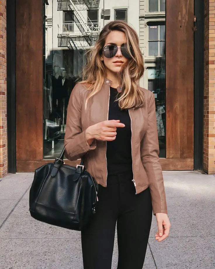 Black leather handbag with a structured shape and top handle complementing a women’s faux leather bomber jacket urban casual coat.