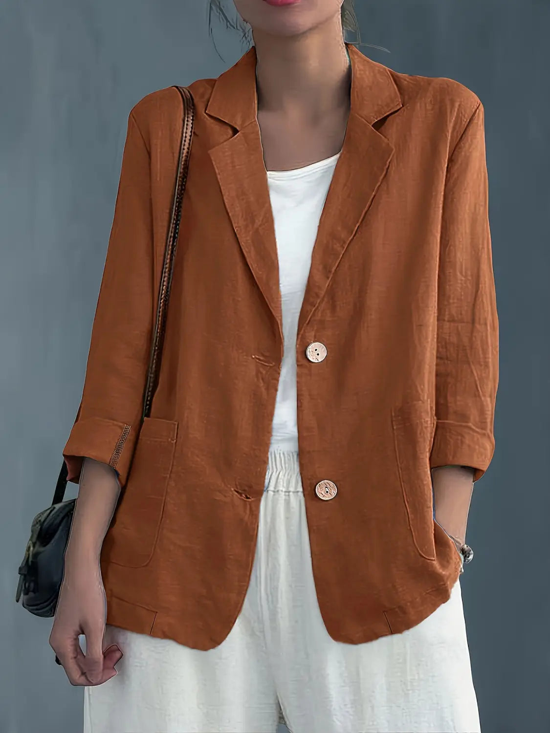 Un blazer de lino color óxido suave para mujer, con ajuste relajado y dos botones delanteros, diseñado para ropa de trabajo casual.