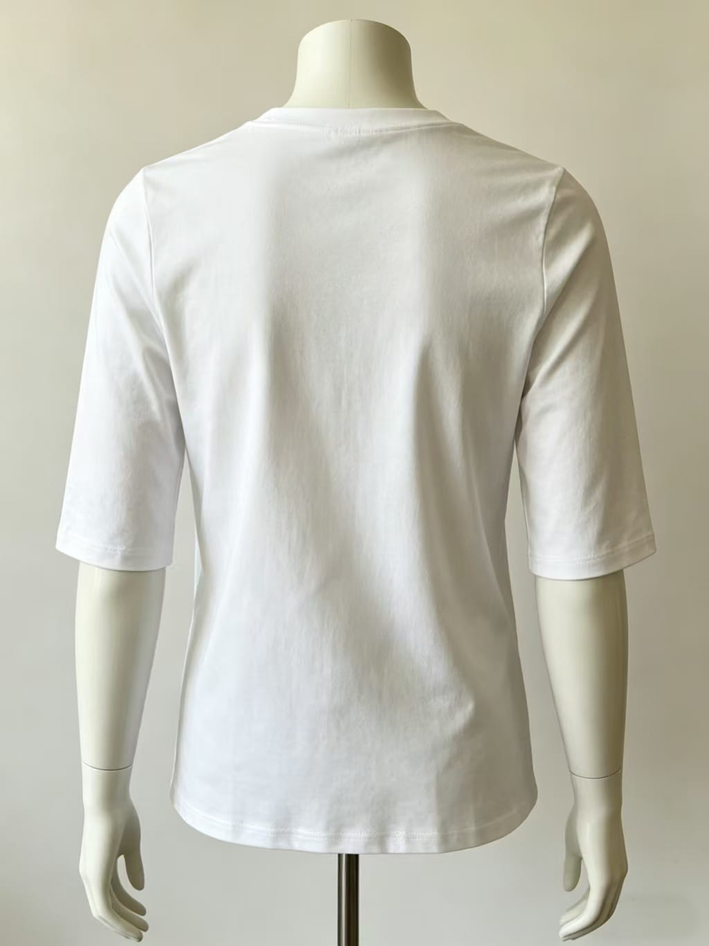 Weißes Baumwoll-Pullover-Oberteil mit Rundhalsausschnitt, legere Ausführung, mit Dreiviertelärmeln, am Schaufensterpüppchen präsentiert.
