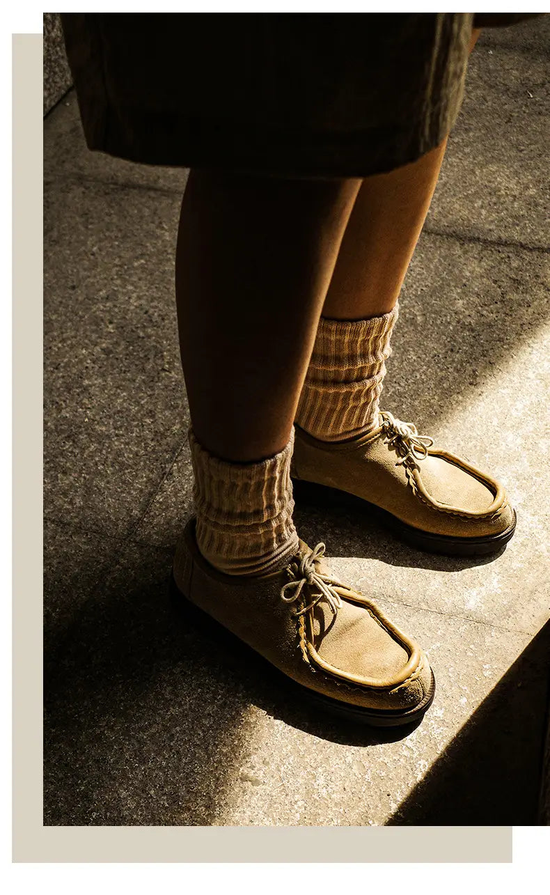 tan suede moccasin shoes with light-colored laces and classic slip-on design paired with vintage ribbed cotton long socks for men.