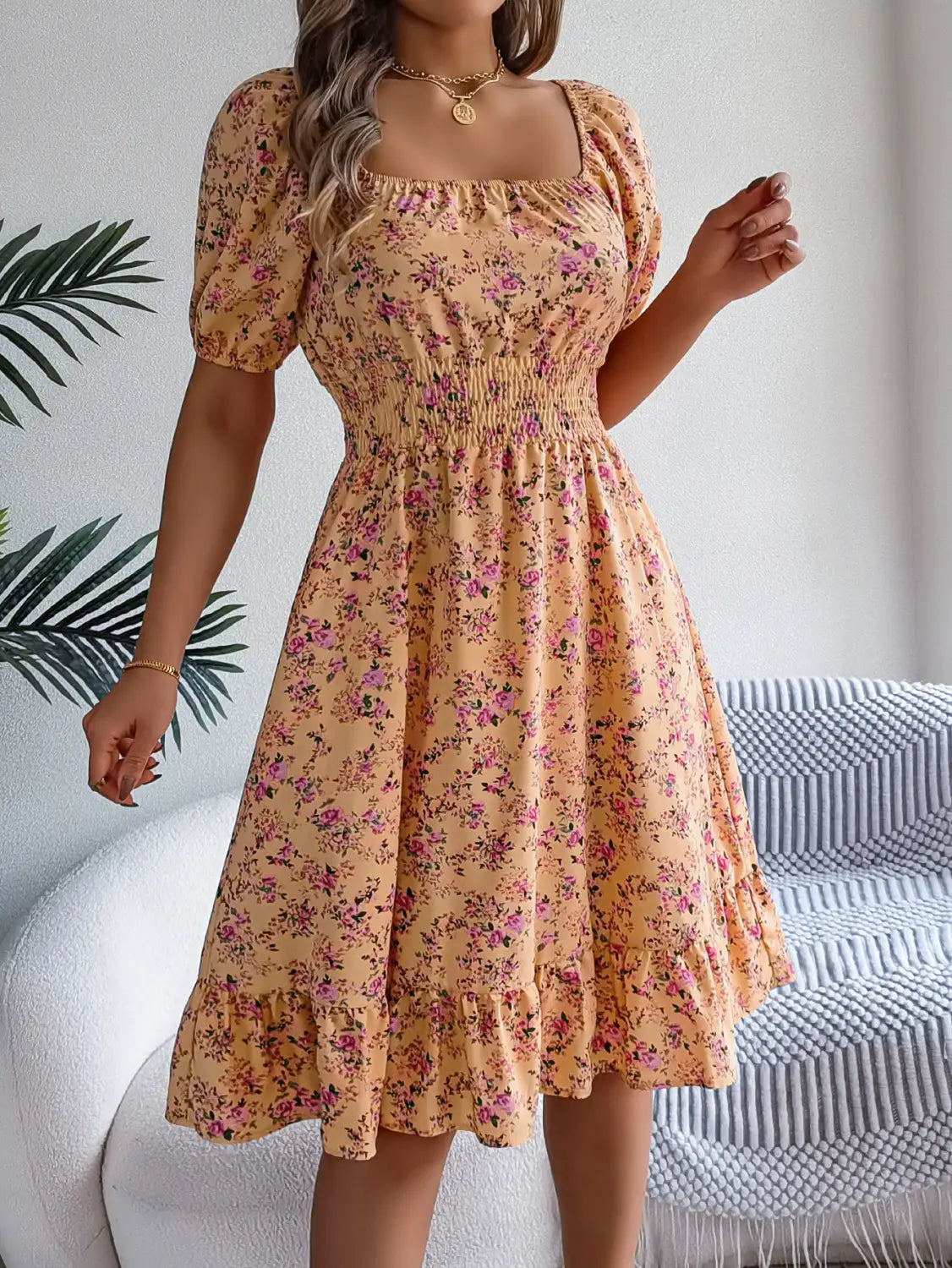 Une robe d’été florale à imprimé pêche clair avec manches courtes bouffantes et encolure carrée, adaptée pour les jours chauds.