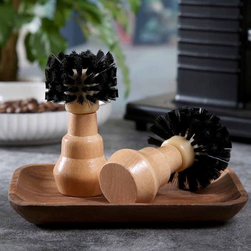 Two wooden-handled coffee machine cleaning brushes with dense black bristles, one standing upright and one lying on its side.