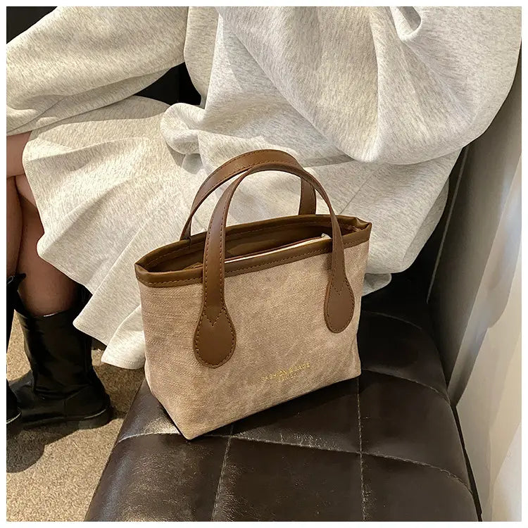 Beige canvas retro bucket bag textured canvas mini tote with brown leather handles and trim for shoulder or handbag use.