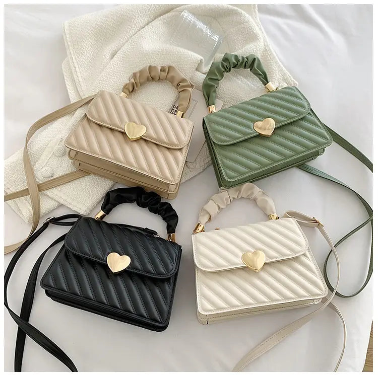 Quilted heart clasp crossbody bag with ruched handle in beige featuring a heart-shaped gold clasp and soft quilted material.