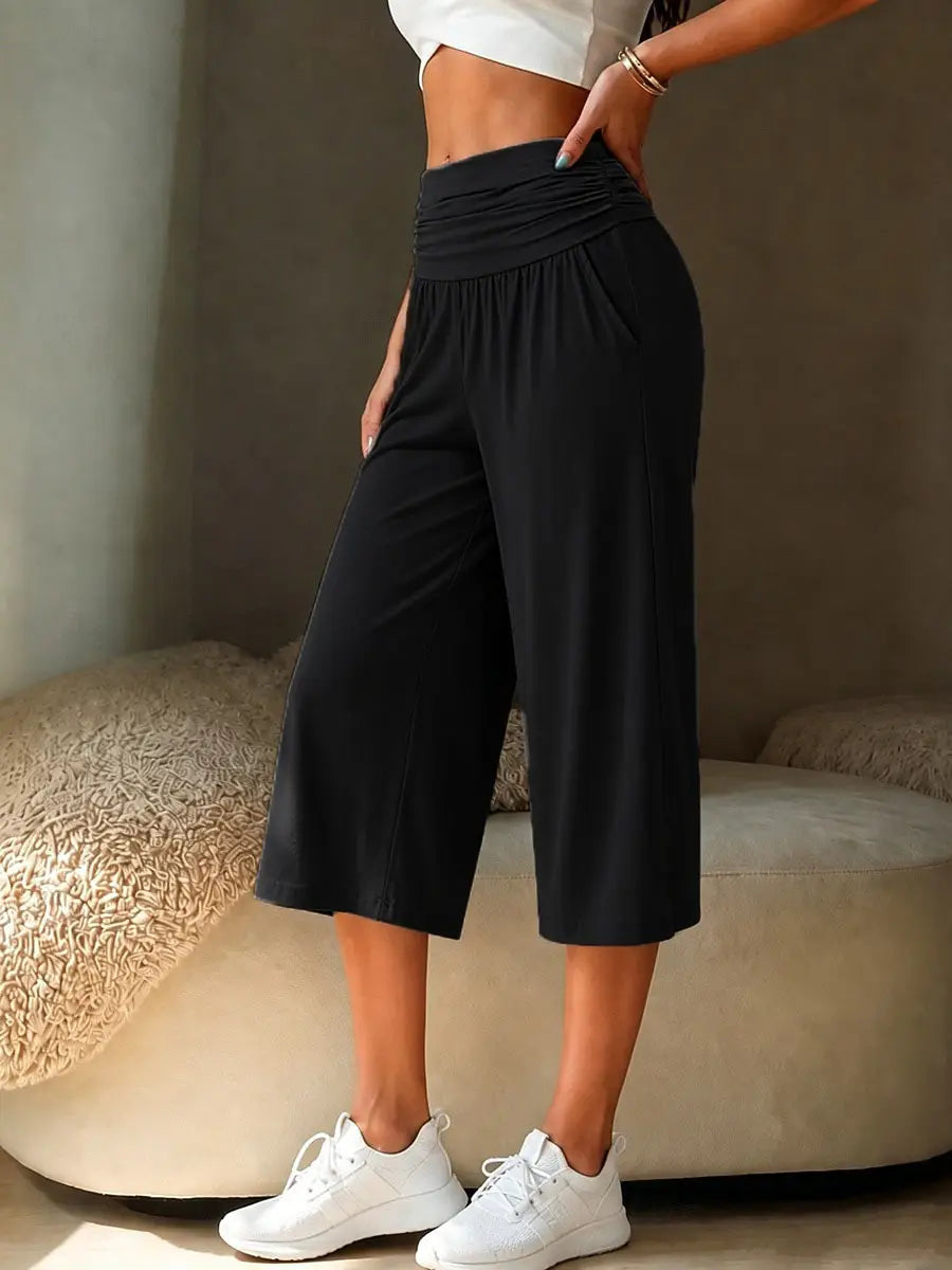 Black high-waisted wide leg cropped pants made of soft stretchy fabric with subtle side pockets for casual wear.