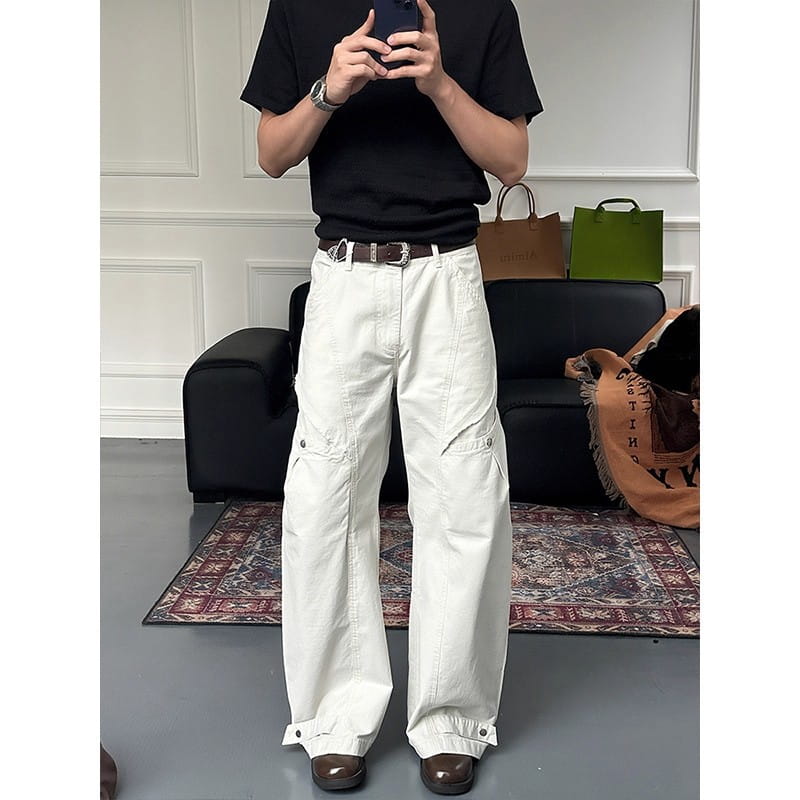 White wide-leg cargo pants featuring multiple pockets and buttoned cuffs designed for a casual and functional style.