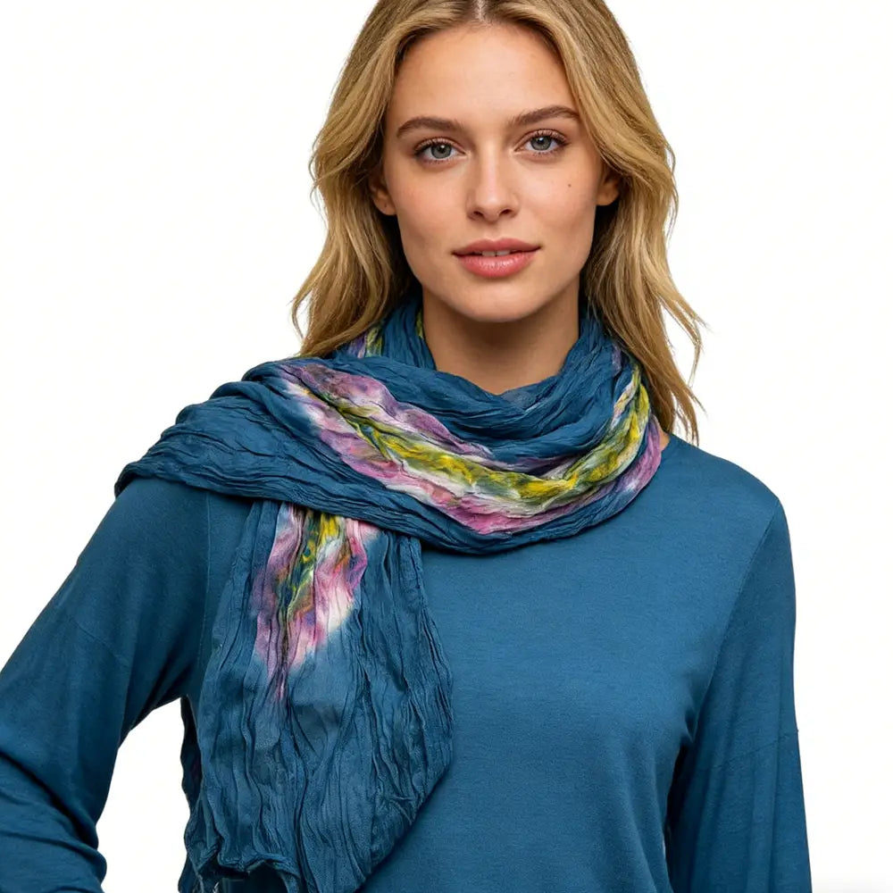 Ein weicher, zerknitterter Baumwollschal in tiefem Petrolton mit einem lebhaften Tie-Dye-Muster aus Farbtönen von Pink, Gelb und Grün.