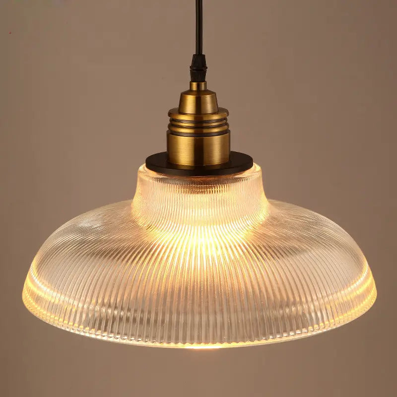 A warm glowing ribbed glass pendant light with a brass metal fixture.