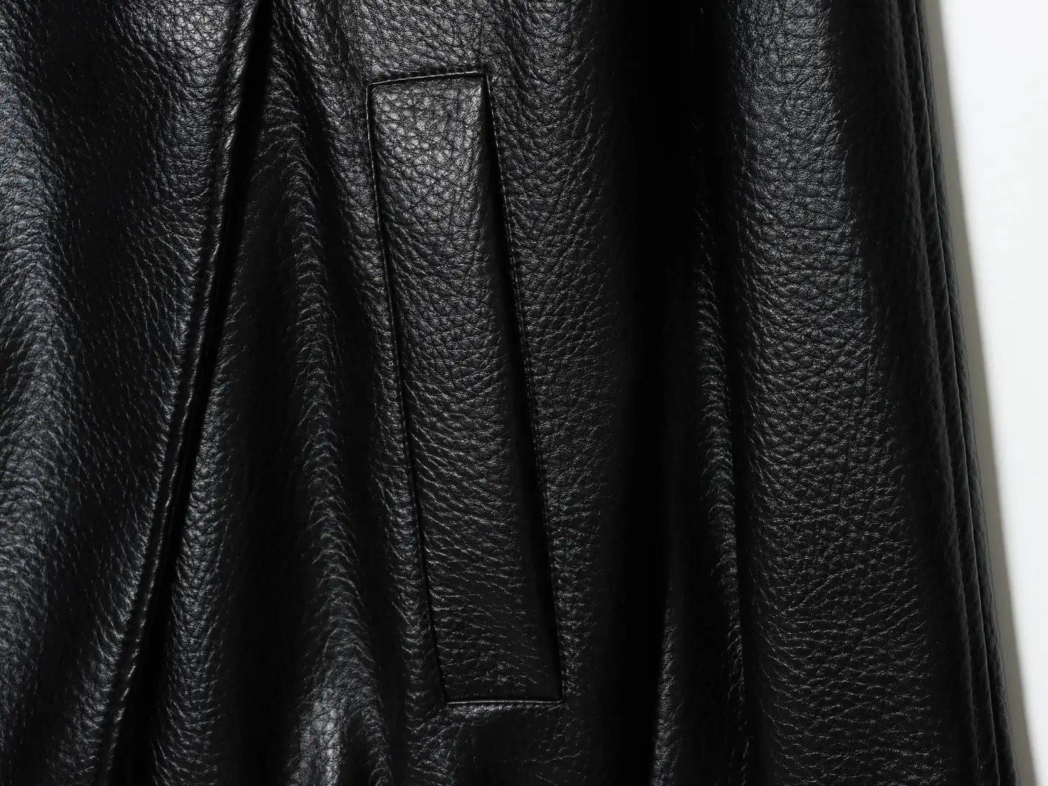 schwarzer Damen-Rock aus Kunstleder mit strukturierter, gepunkteter Oberfläche und vertikalem Detail der Naht, passend zur schwarzen Damen-Motorradjacke mit hohem Stehkragen aus Kunstleder.