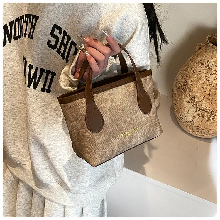 Beige and brown retro bucket bag textured canvas shoulder handbag with leather handles and a subtle gold logo.