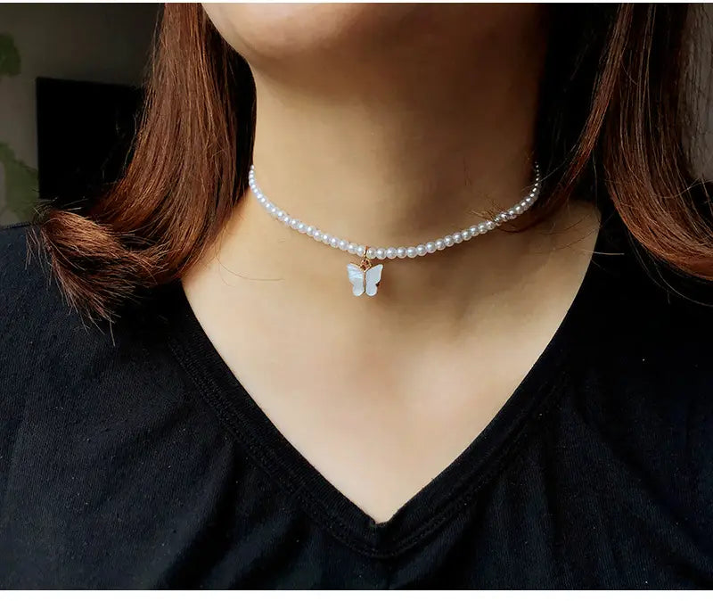 Elegant pearl butterfly charm choker necklace featuring a delicate white butterfly pendant on a pearl strand.