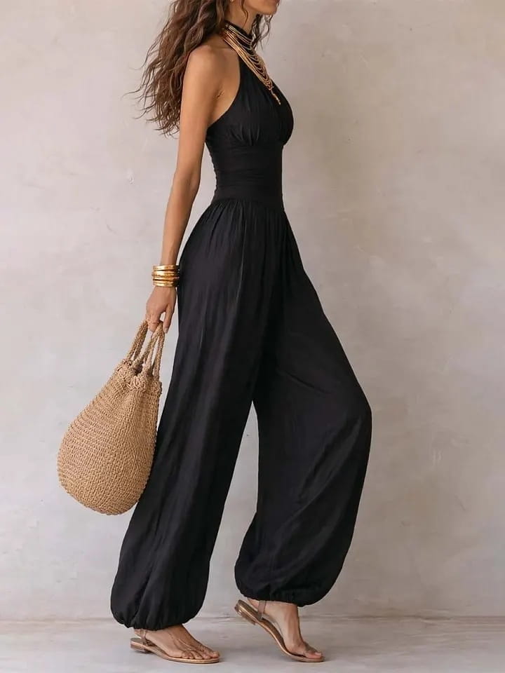 Mono tipo halter de pierna ancha en color negro con tela fluida y cintura fruncida en un tono negro elegante.