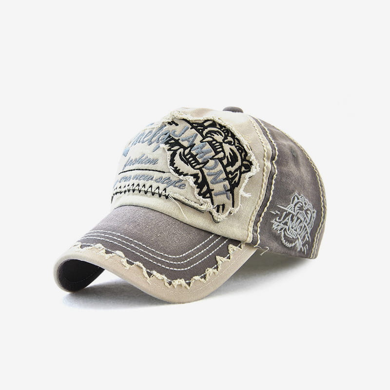 beige and gray distressed baseball cap featuring a black embroidered tiger patch on the front.
