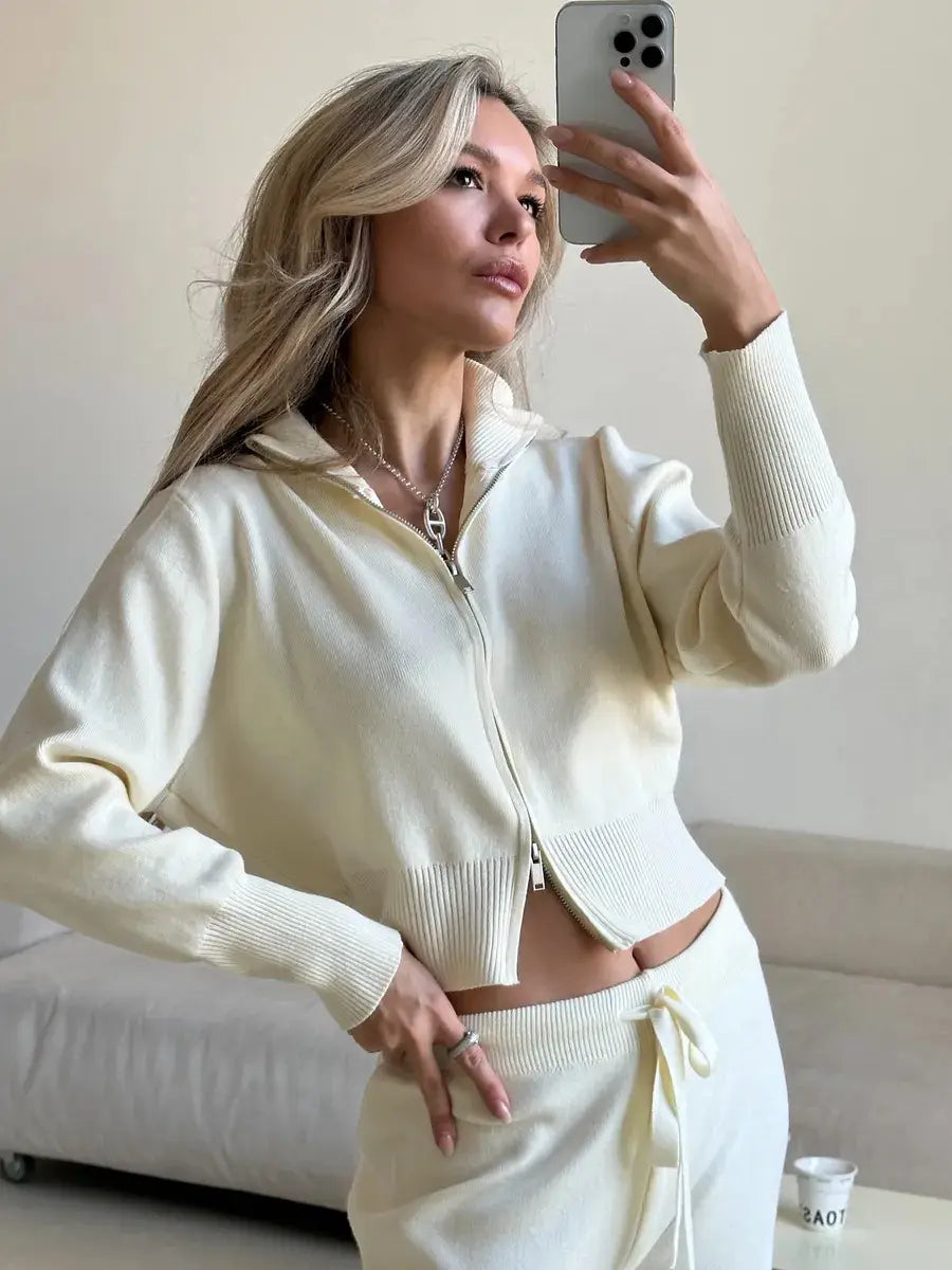 Cream-colored cropped knit zip-up jacket with ribbed cuffs and hem featured in a women’s knit zip-up cardigan and wide leg pant set.