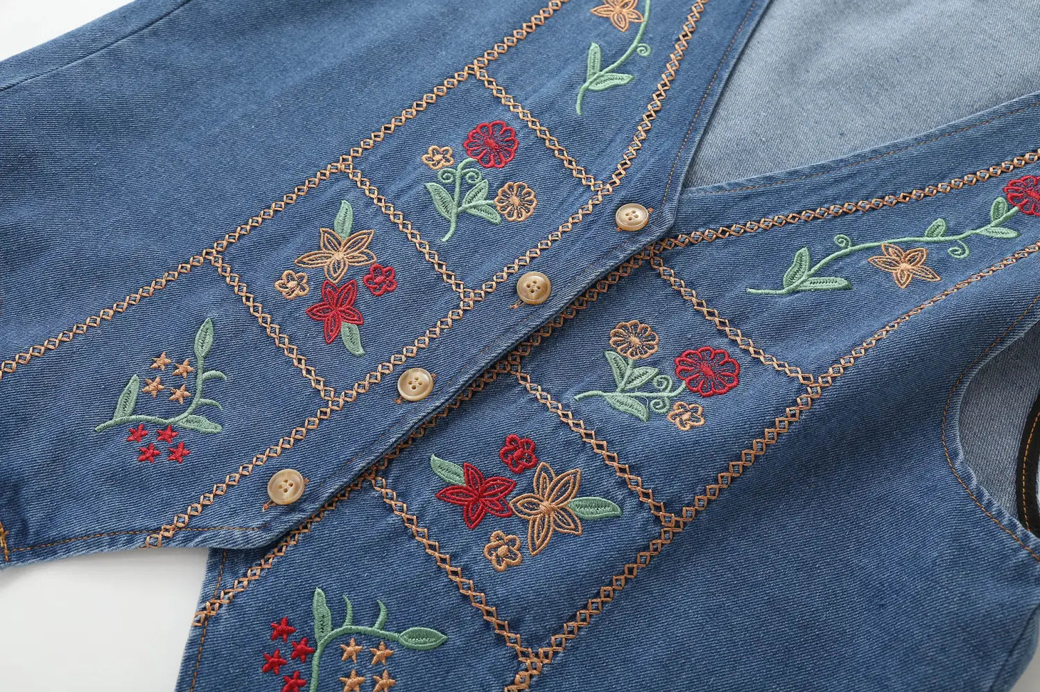Blaues Jeansweste mit farbenfroher roter grüner und beiger floraler Stickerei auf einem Diamantmuster-Design, betitelt bestickte florale Jeansweste.