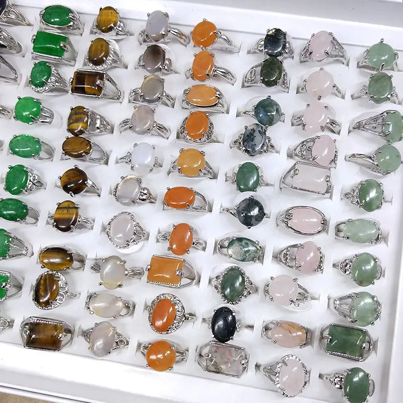 A collection of natural gemstone silver tone statement rings featuring oval and rectangular cabochon gemstones in green, orange, pink, brown, and black.