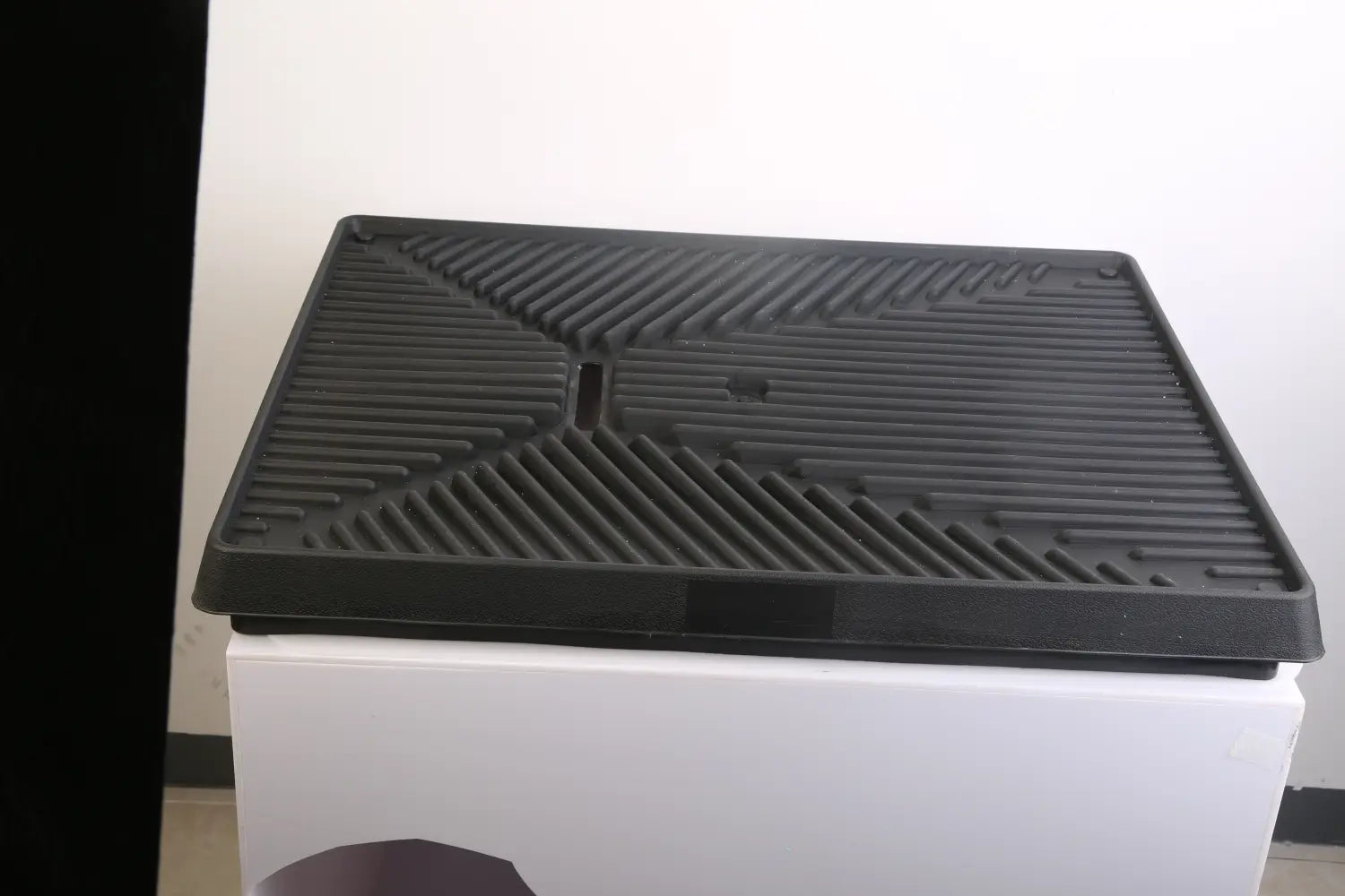 black rubberized dog potty training mat tray with a textured ribbed surface and geometric pattern designed for artificial grass use