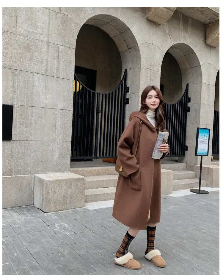 Eine gemütliche Winter-Outdoorjacke mittlerer Länge aus Wolle mit Kapuze in Braun, mit langem Design und vorderen Taschen.