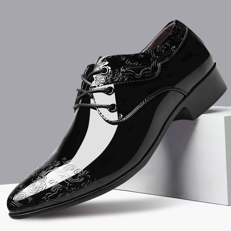 Black patent leather men’s formal business shoe with glossy finish and intricate silver embossed cloud patterns on the toe side and vamp.