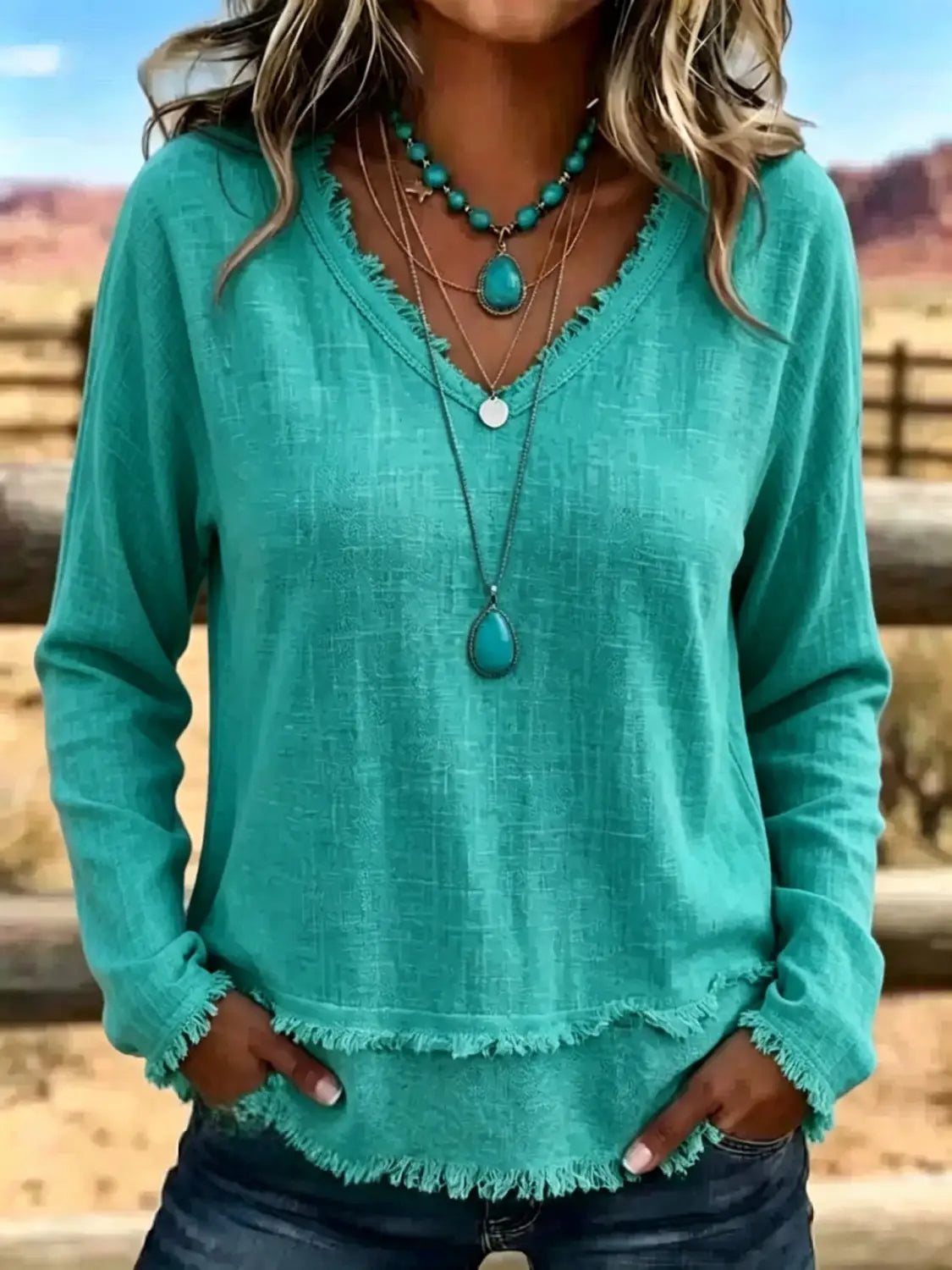 T-shirt décontracté pour femmes à manches longues et encolure en V vert canard, avec ourlet effiloché, conçu comme un haut casual.