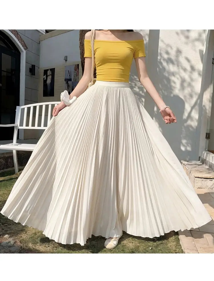 Dame, die ein gelbes Oberteil mit Off-Shoulder-Ausschnitt trägt, kombiniert mit einem fließenden weißen plissierten Chiffon-Maxirock für Damen