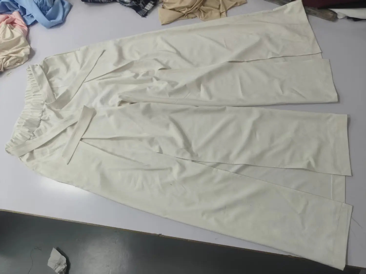 Une paire de pantalons amples à taille haute ivoire, avec une taille élastique et une coupe décontractée, adaptée à un port quotidien.